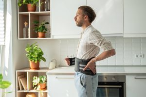 Ein Mann trägt ein Stützkorsett für den unteren Rücken zur Behandlung eines Leistenbruchs und zur Entlastung der Wirbelsäule.
